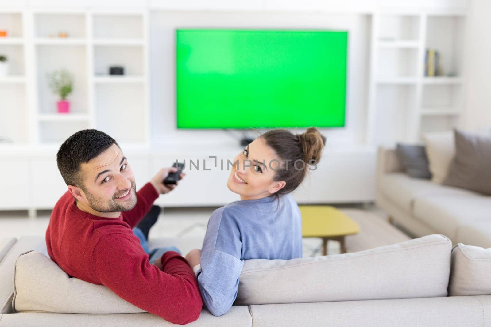 Young couple on the sofa watching television together in their luxury home