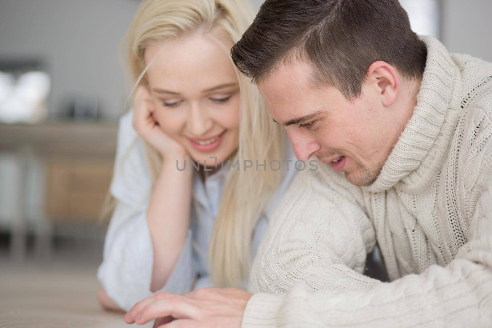 Young Couple on the floor in front of fireplace surfing internet using digital tablet on cold winter day