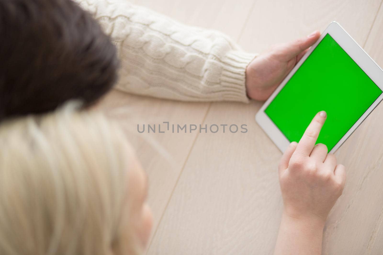 Young Couple on the floor in front of fireplace surfing internet using digital tablet on cold winter day