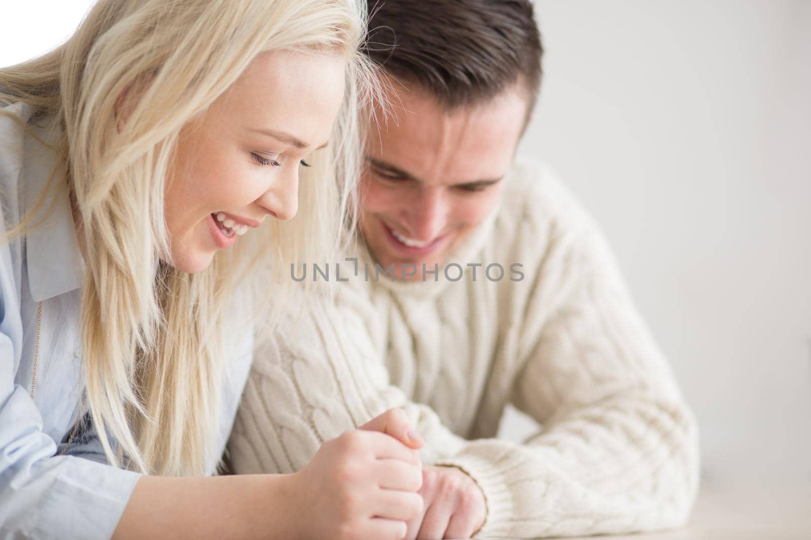 Young Couple on the floor in front of fireplace surfing internet using digital tablet on cold winter day