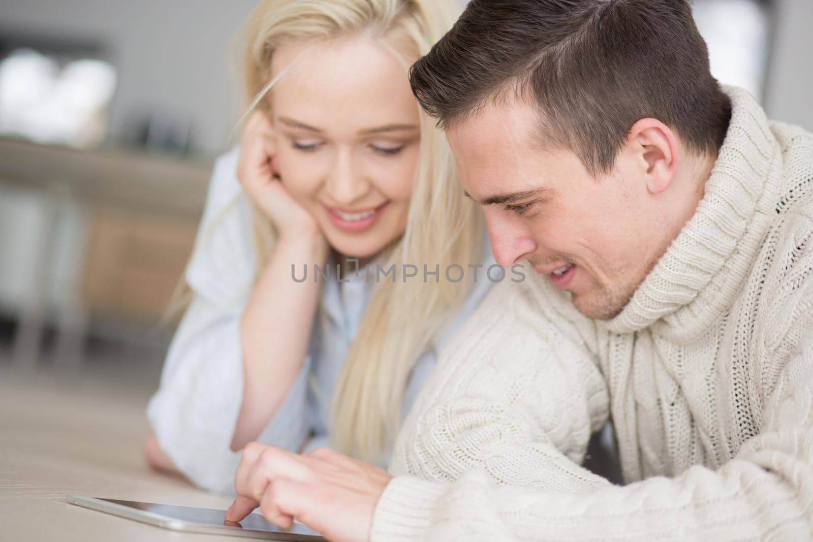 Young Couple on the floor in front of fireplace surfing internet using digital tablet on cold winter day