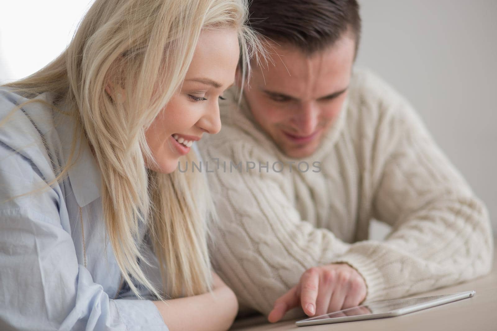 Young Couple on the floor in front of fireplace surfing internet using digital tablet on cold winter day