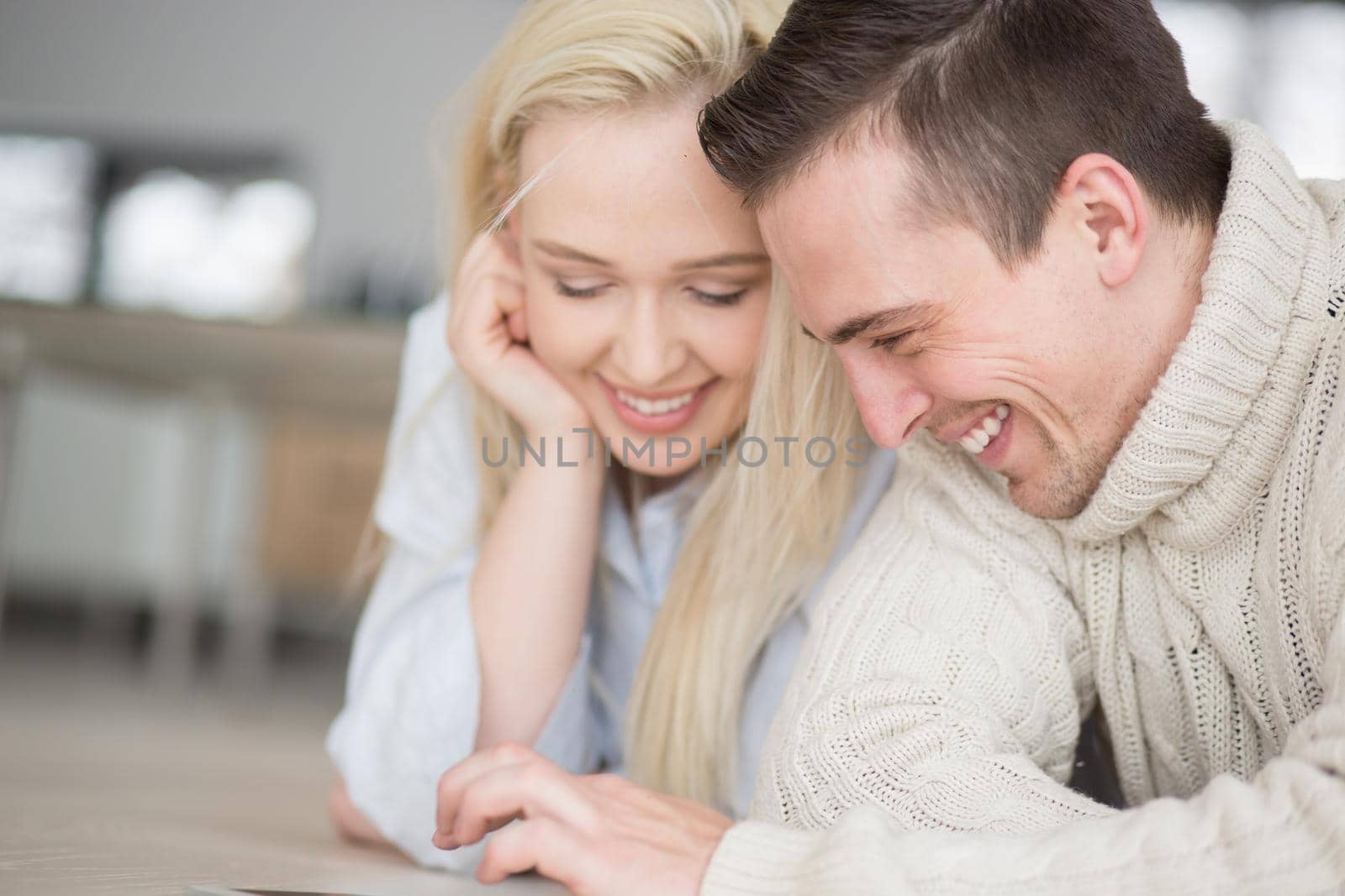 Young Couple on the floor in front of fireplace surfing internet using digital tablet on cold winter day