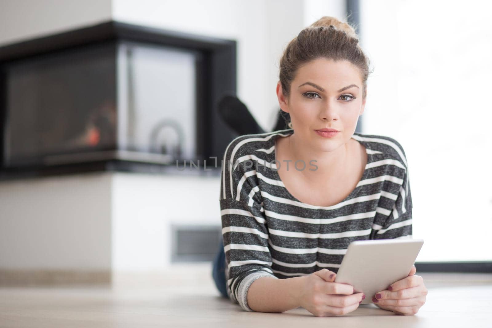 woman using tablet computer in front of fireplace by dotshock