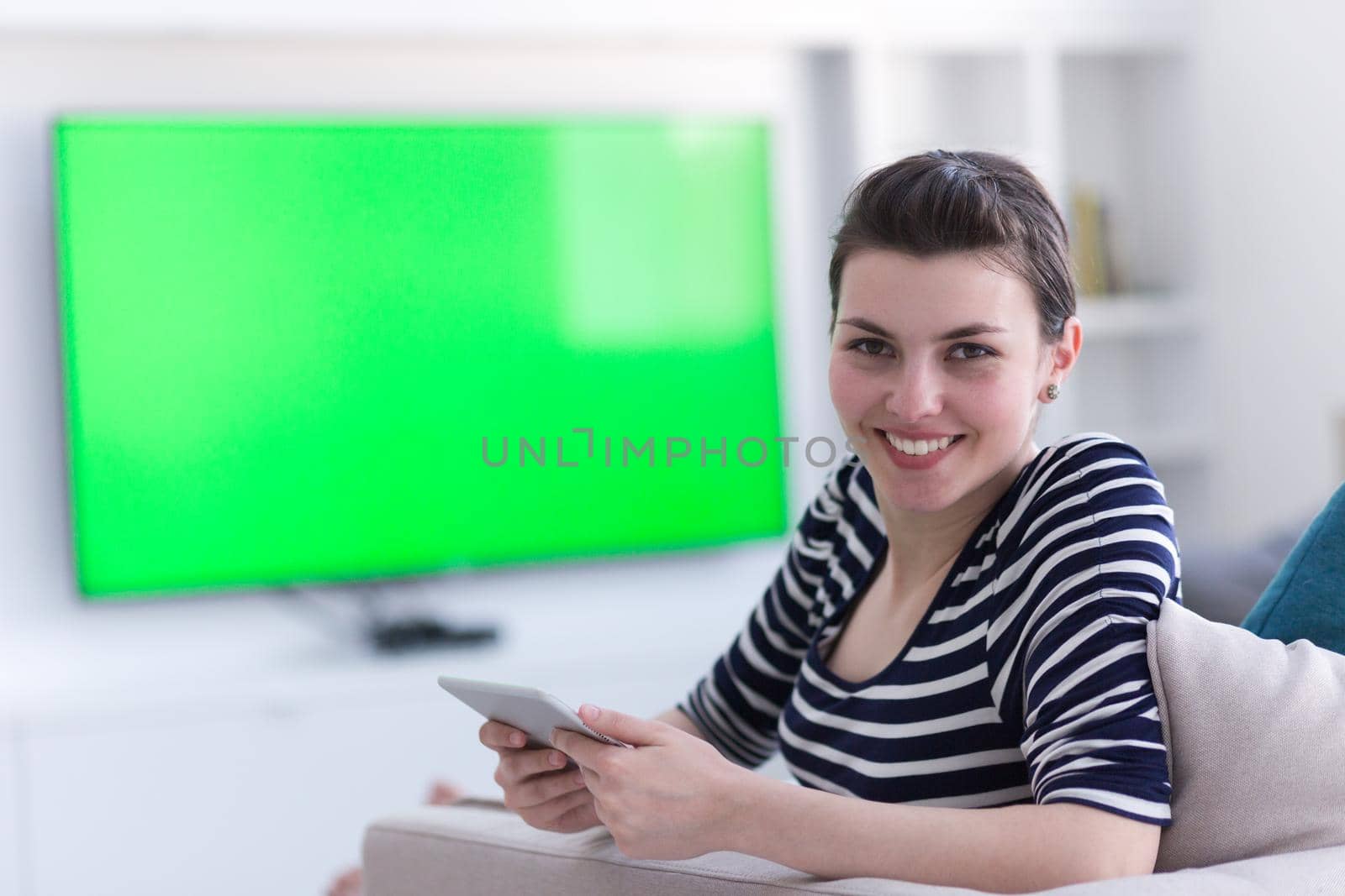 young happy woman on sofa using tablet computer at luxury home