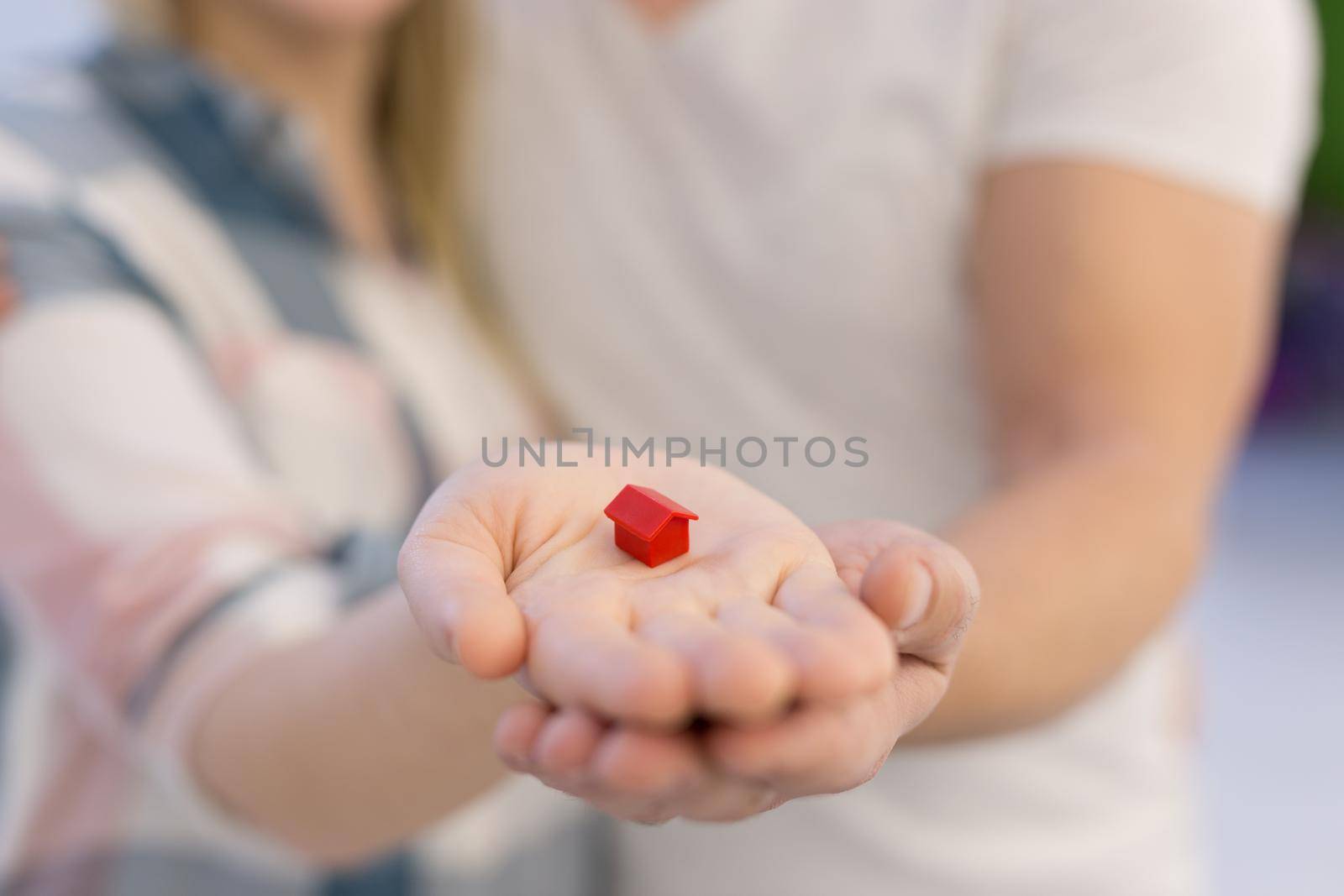 couple showing small red house in hands by dotshock