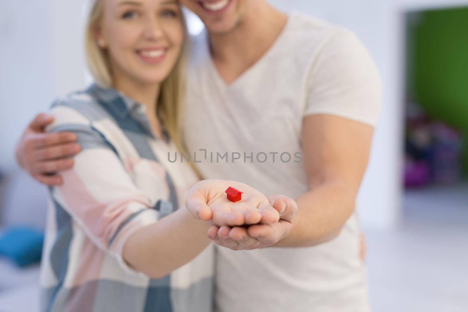 couple showing small red house in hands by dotshock