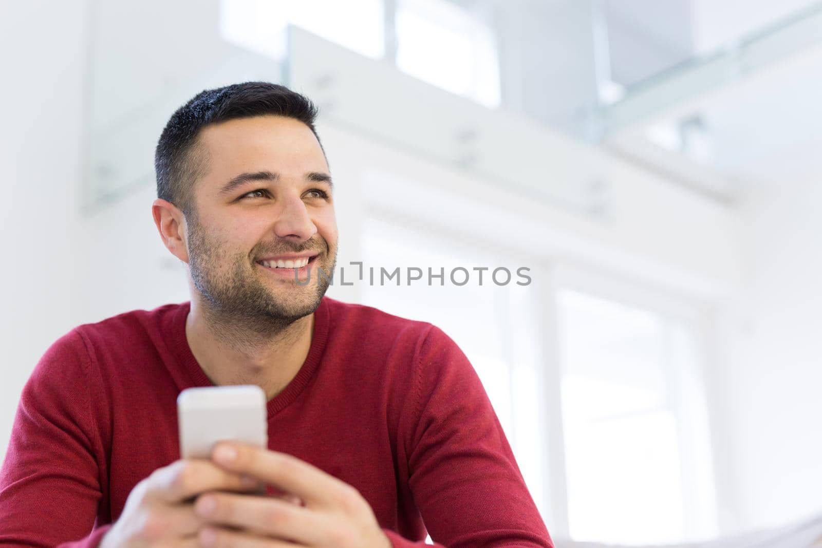 Handsome casual young man using a mobile phone at  home