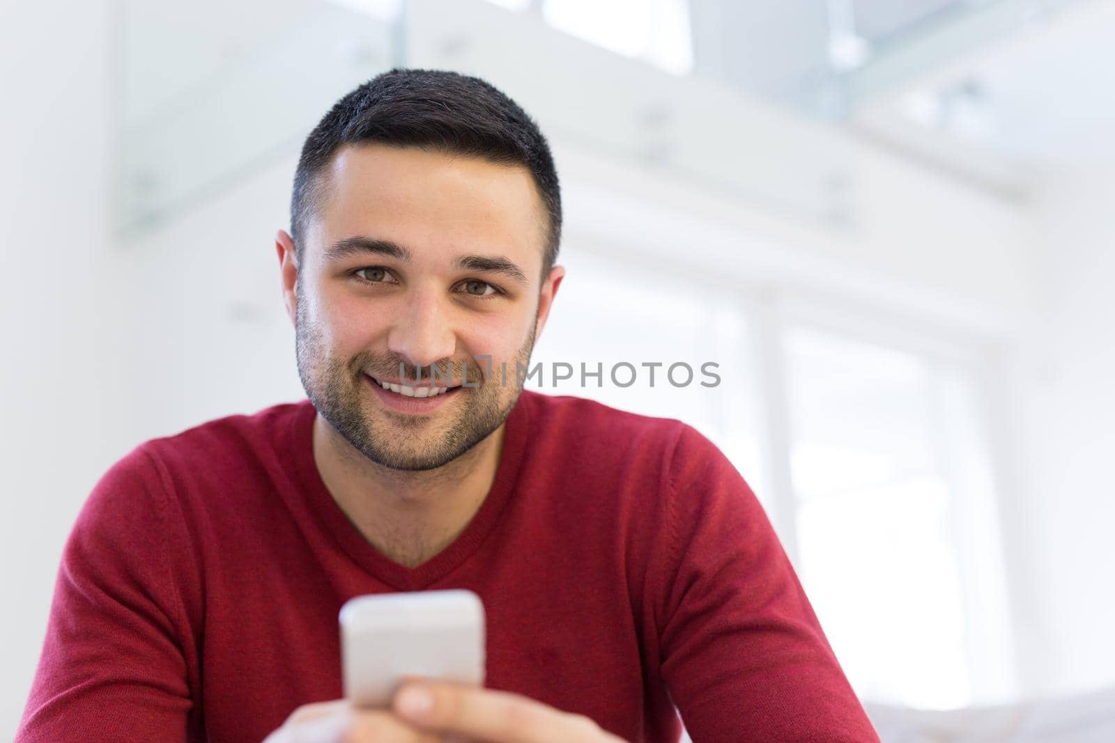 Handsome casual young man using a mobile phone at  home