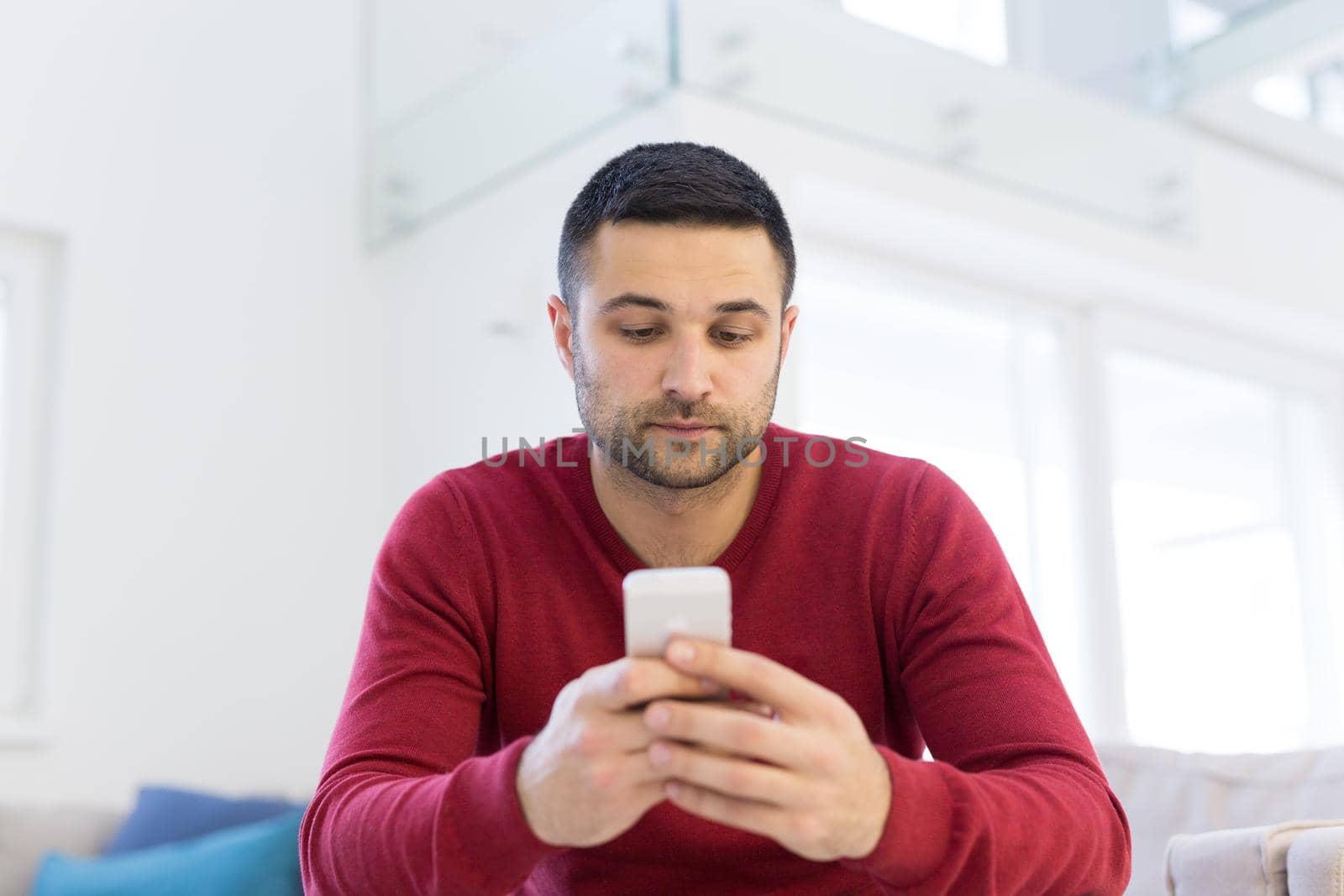 Handsome casual young man using a mobile phone at  home