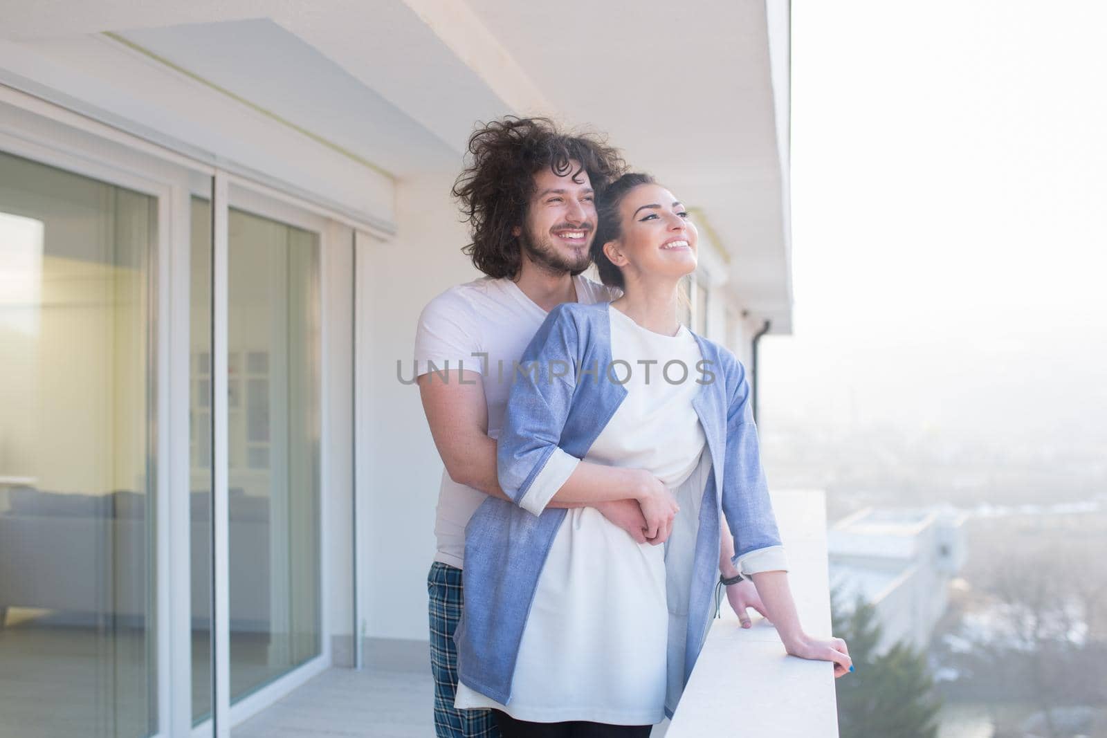 Couple in love sharing emotions and happiness while hugging on the balcony at home