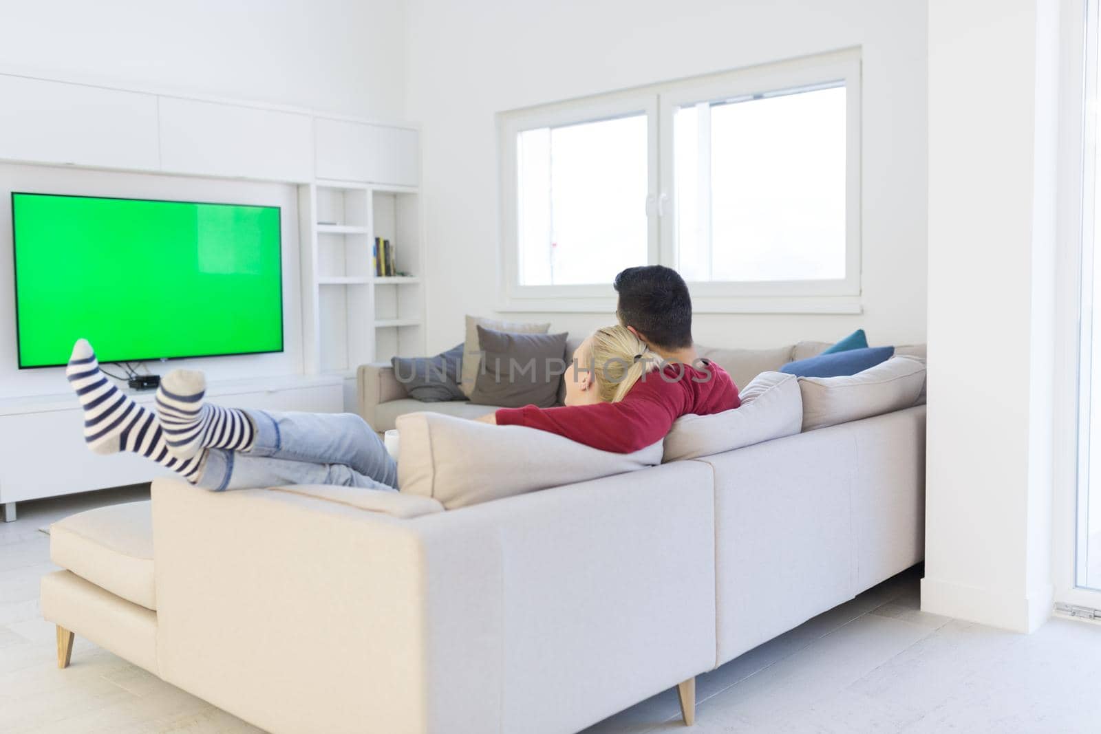 Young couple on the sofa watching television together in their luxury home