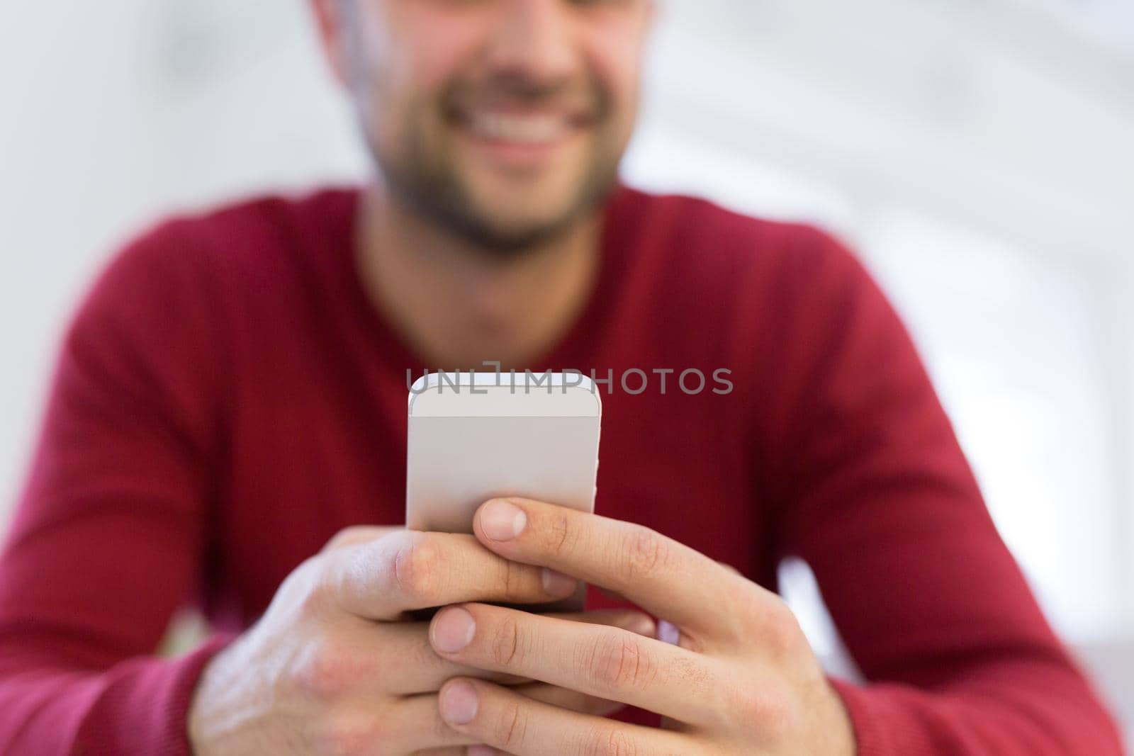 Handsome casual young man using a mobile phone at  home