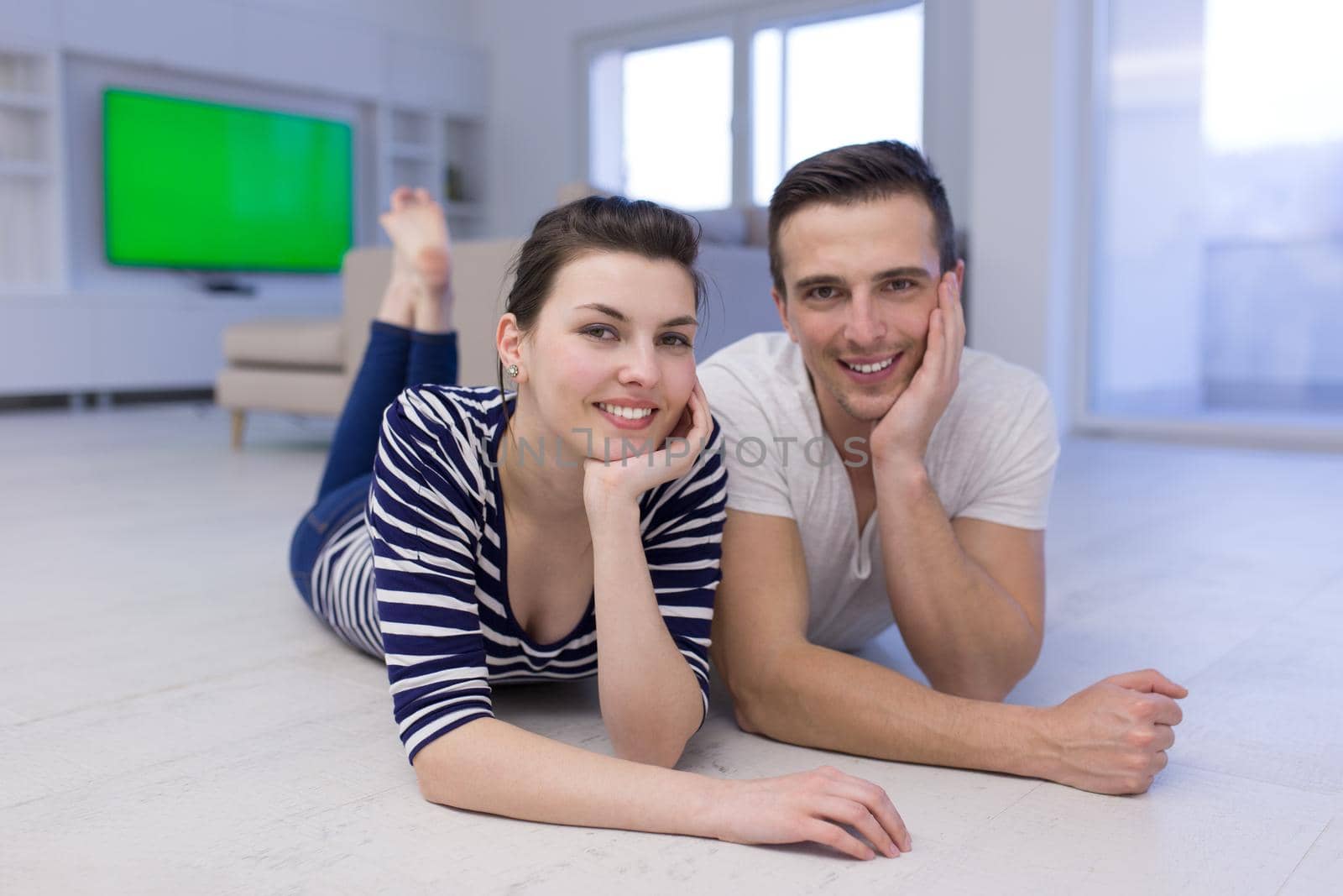 Lovely couple enjoying free time lying on the floor in their living room at home