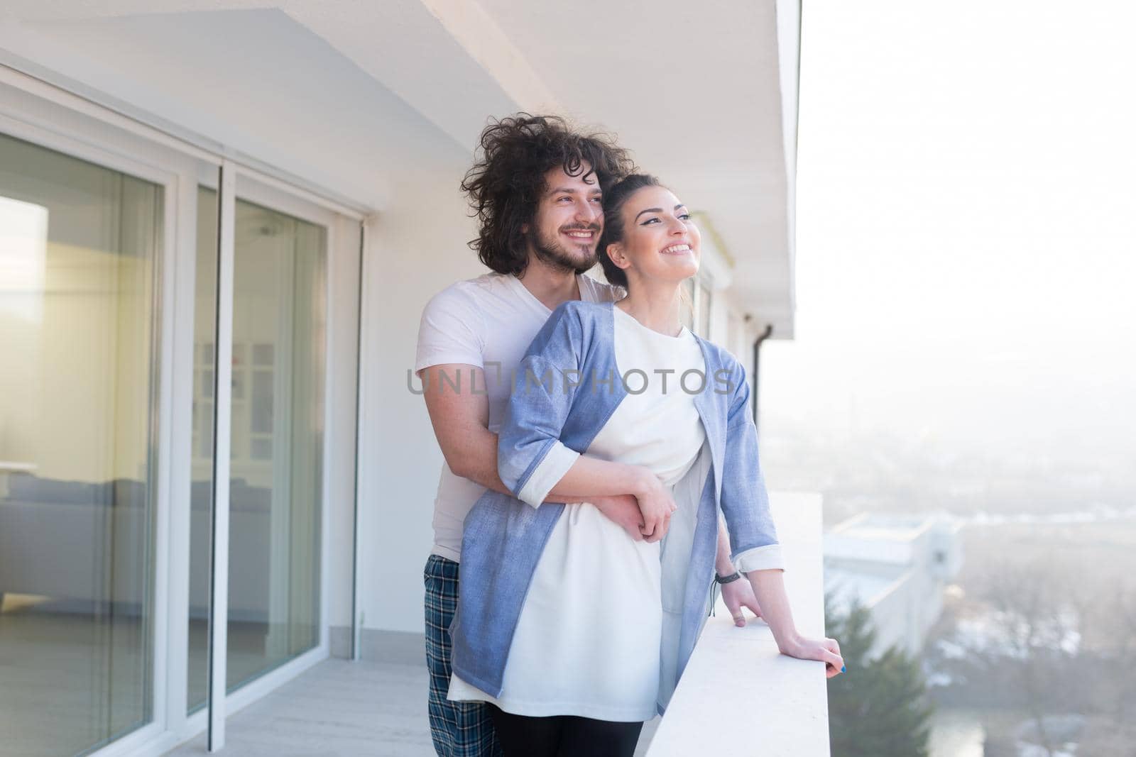 Couple in love sharing emotions and happiness while hugging on the balcony at home