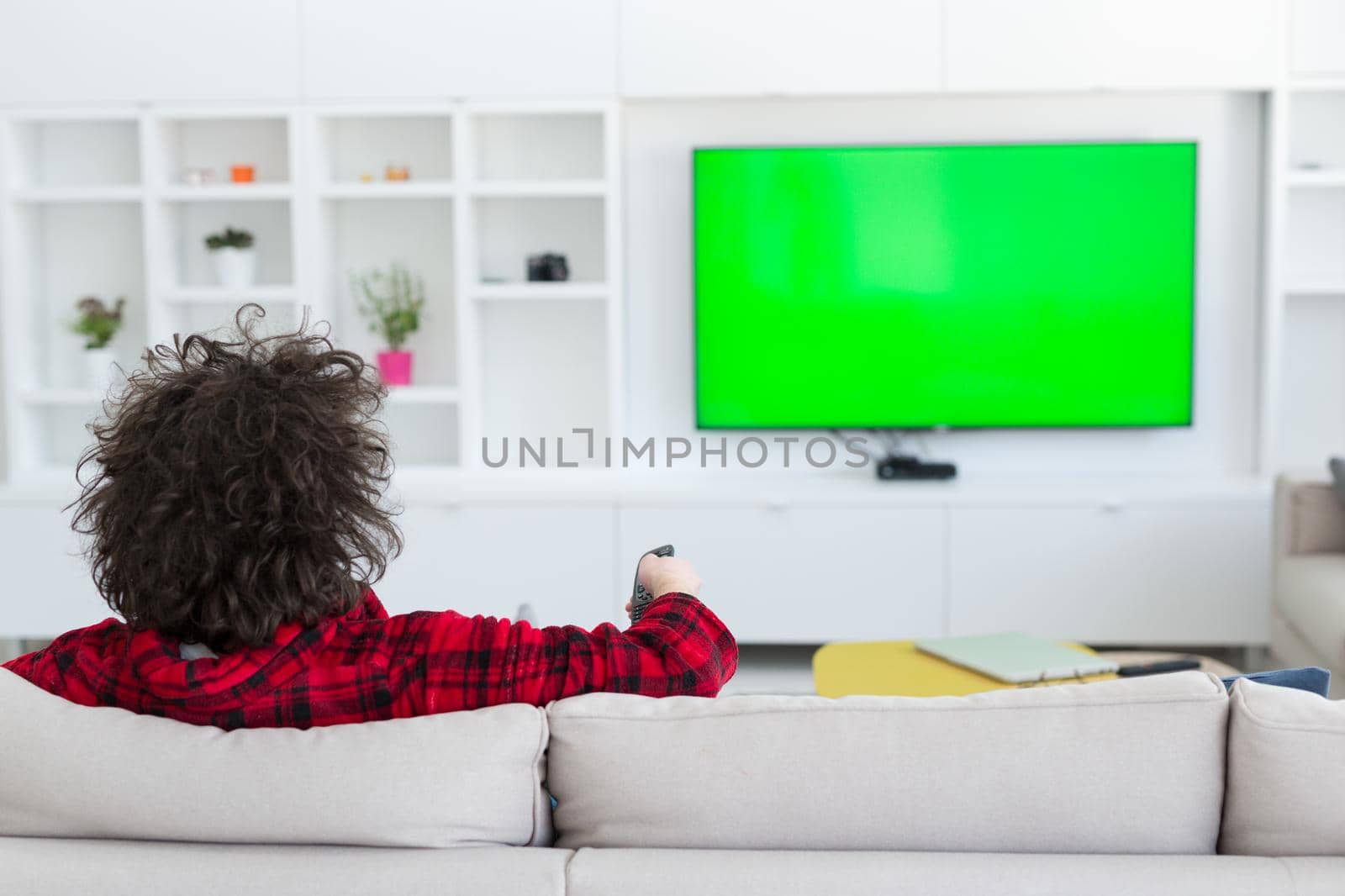 young handsome man in bathrobe enjoying free time watching television in his luxury home