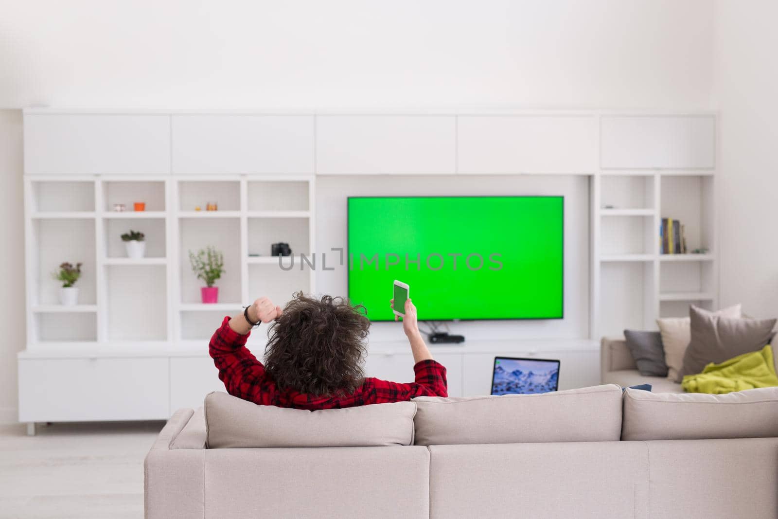 young handsome man in bathrobe enjoying free time watching television in his luxury home