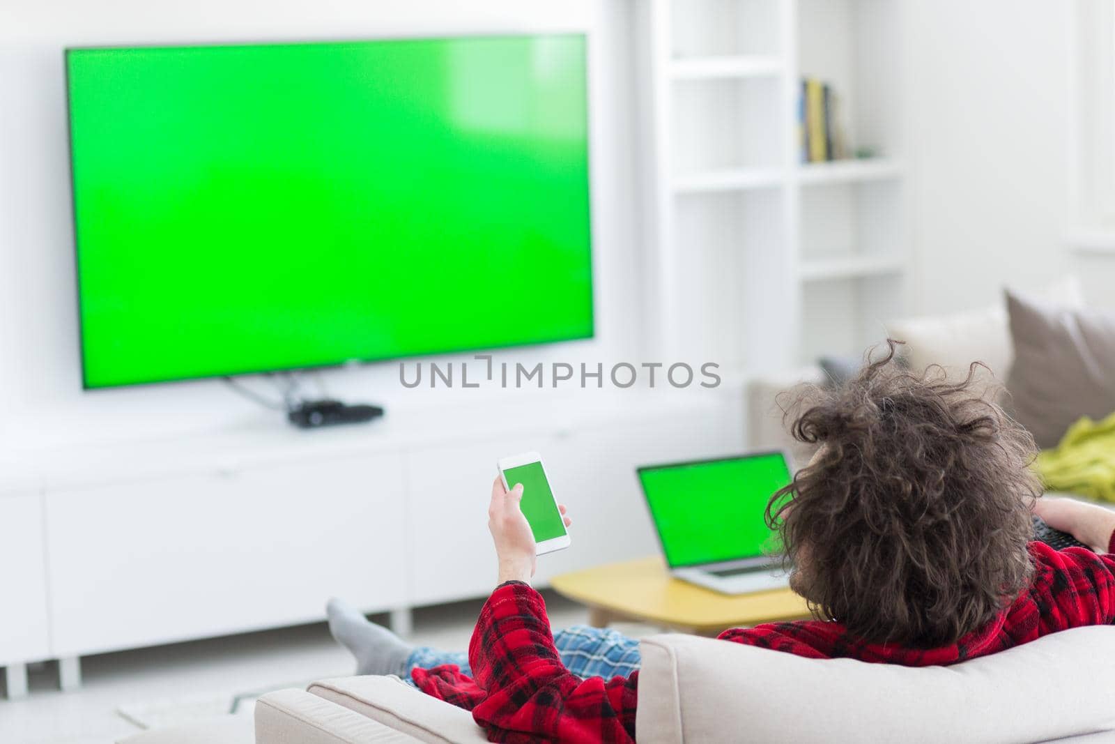 young handsome man in bathrobe enjoying free time watching television in his luxury home