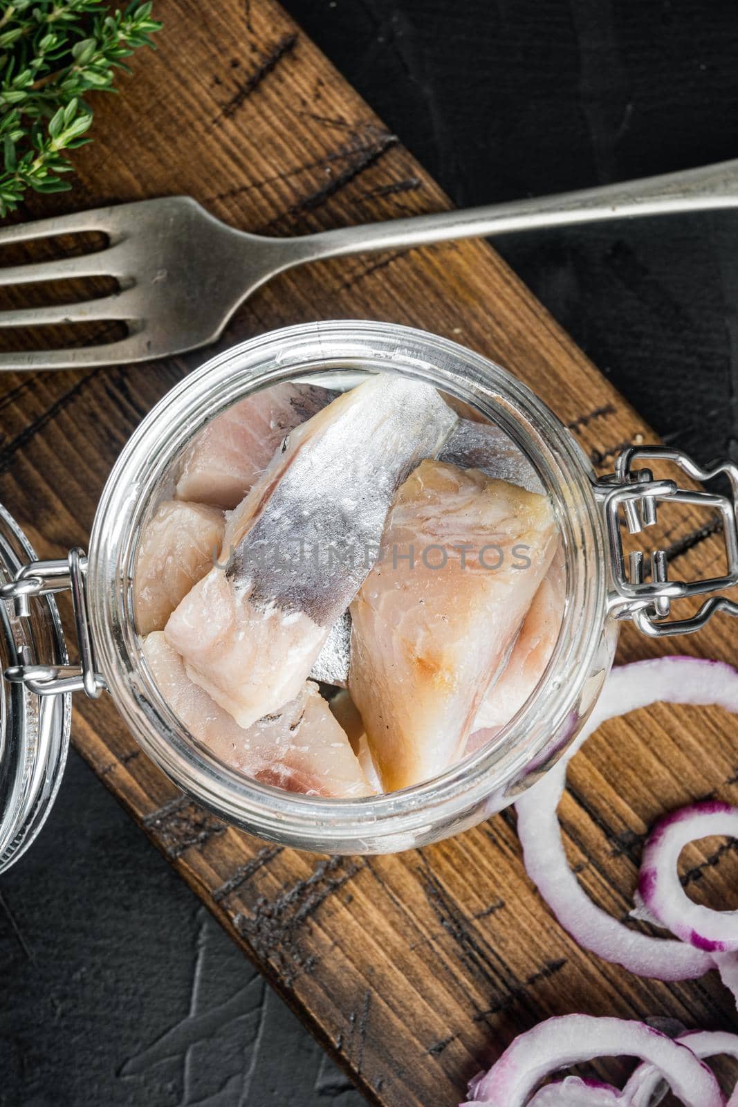 Herring fillet in oil, on black background, top view flat lay