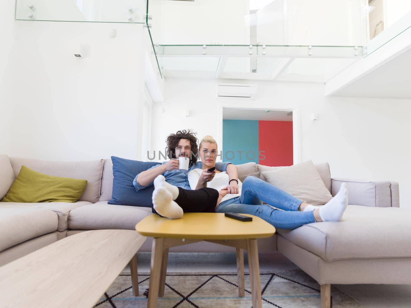 Young couple on the sofa watching television together in their luxury home