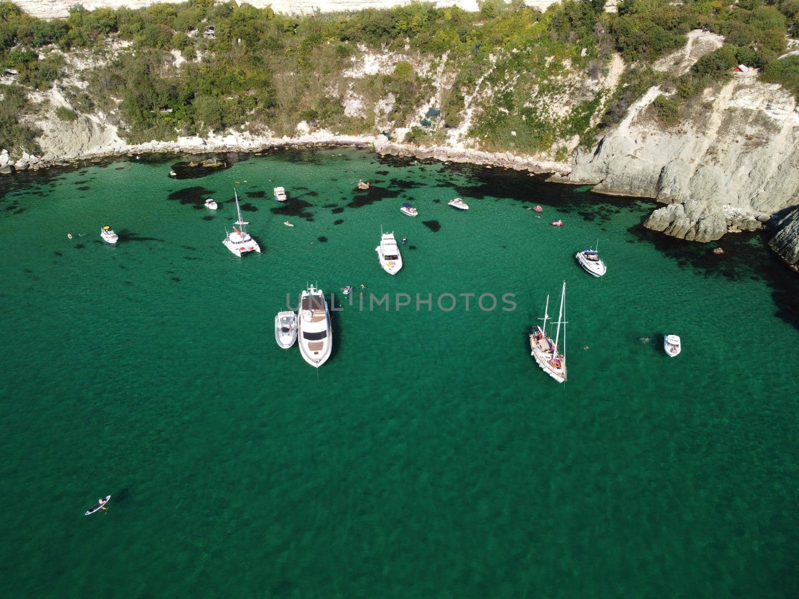 Sea landscape with rocky coastline on sunset time with cloudy sky. Yachts in the Sea on a background of rocky shores. The concept of perfect place for summer travel and rest.