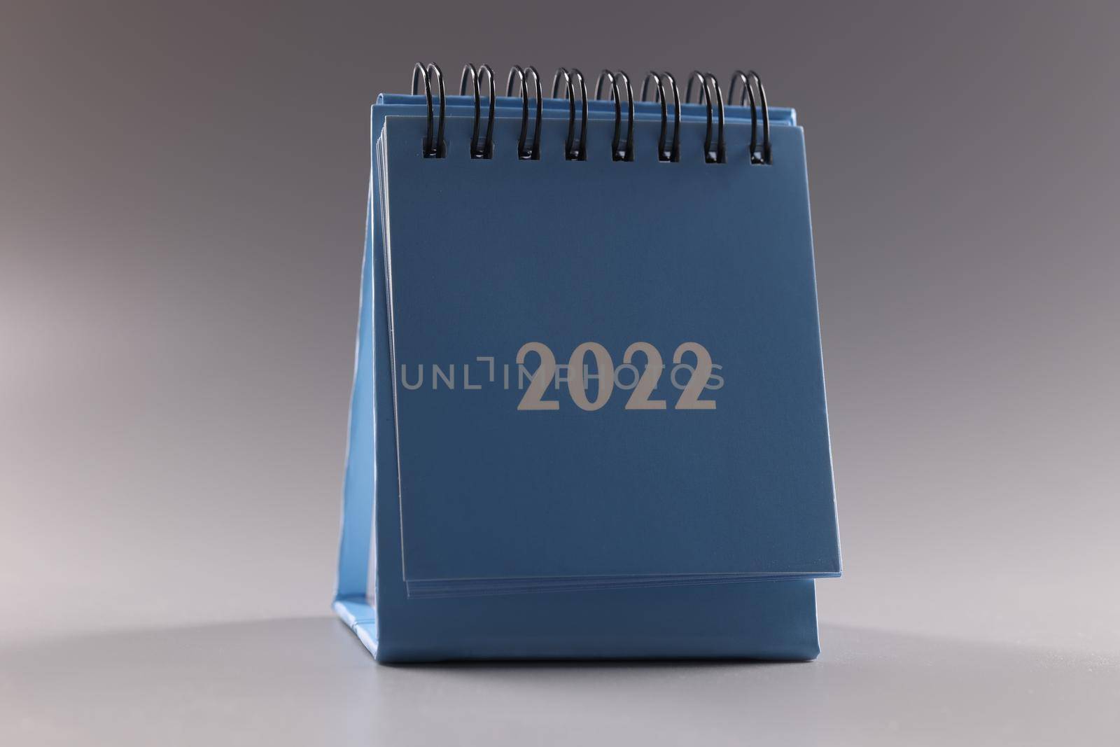 Blue loose-leaf calendar 2022 on gray background. Planning tasks for year concept