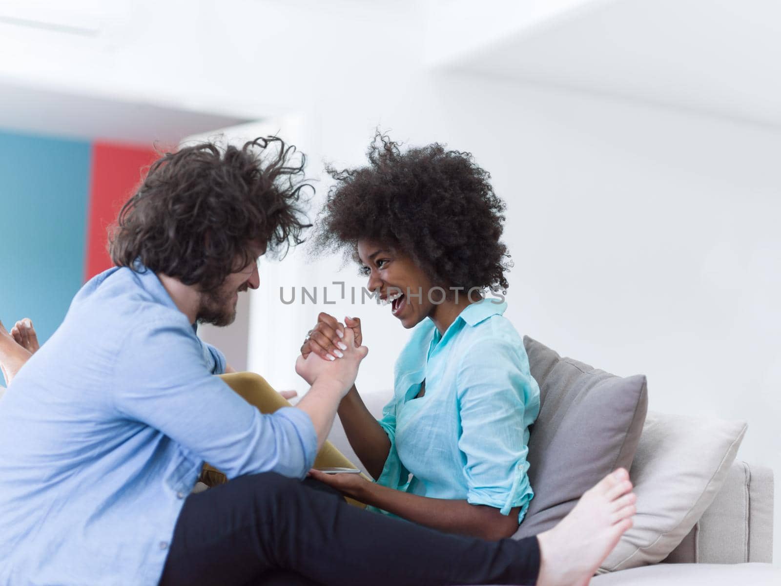 Young multiethnic couple sitting on a sofa in the luxury living room, using a tablet computer