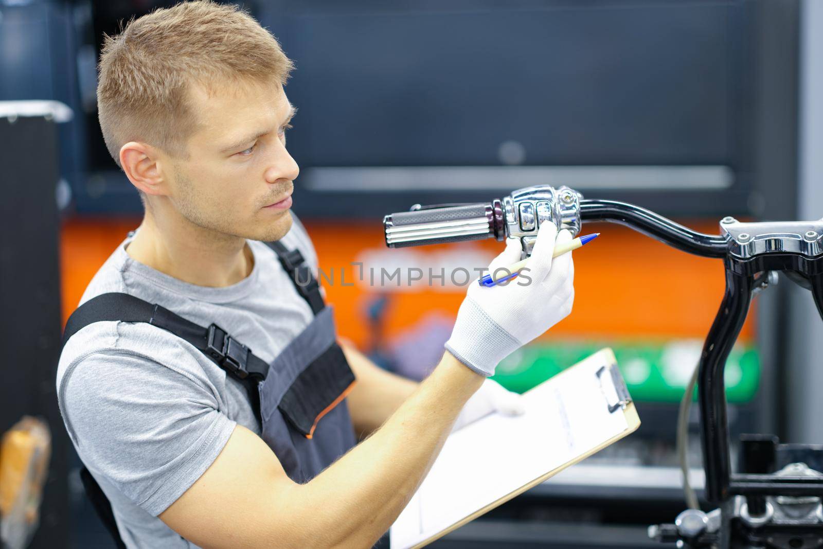 Young locksmith conducts diagnostics of motorcycle in service center. Motorcycle warranty service