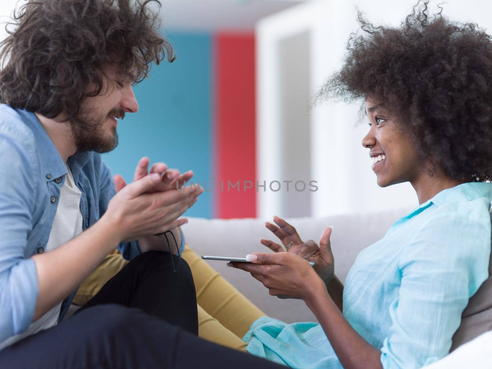 Young multiethnic couple sitting on a sofa in the luxury living room, using a tablet computer