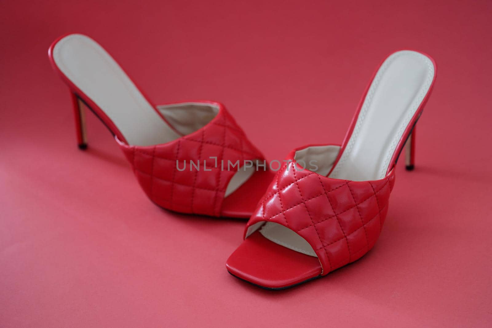 Red leather female sandals with heels on red background. Summer shoes concept