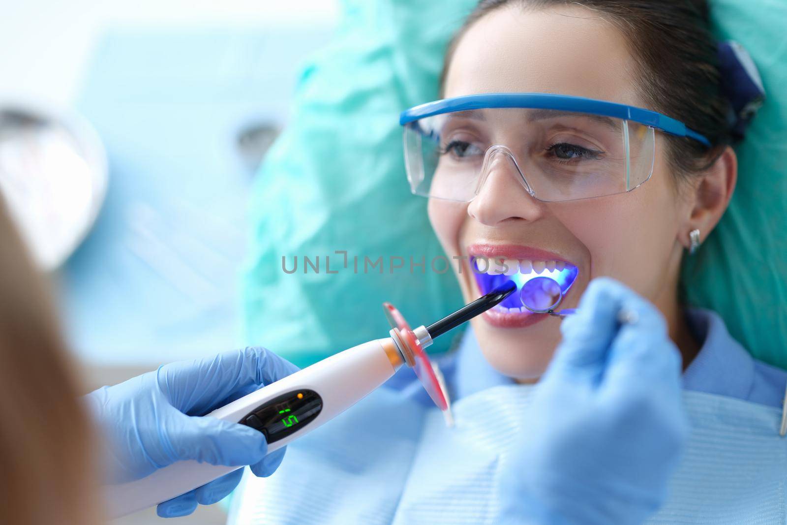 Dentist works with dental polymerization lamp in oral cavity by kuprevich