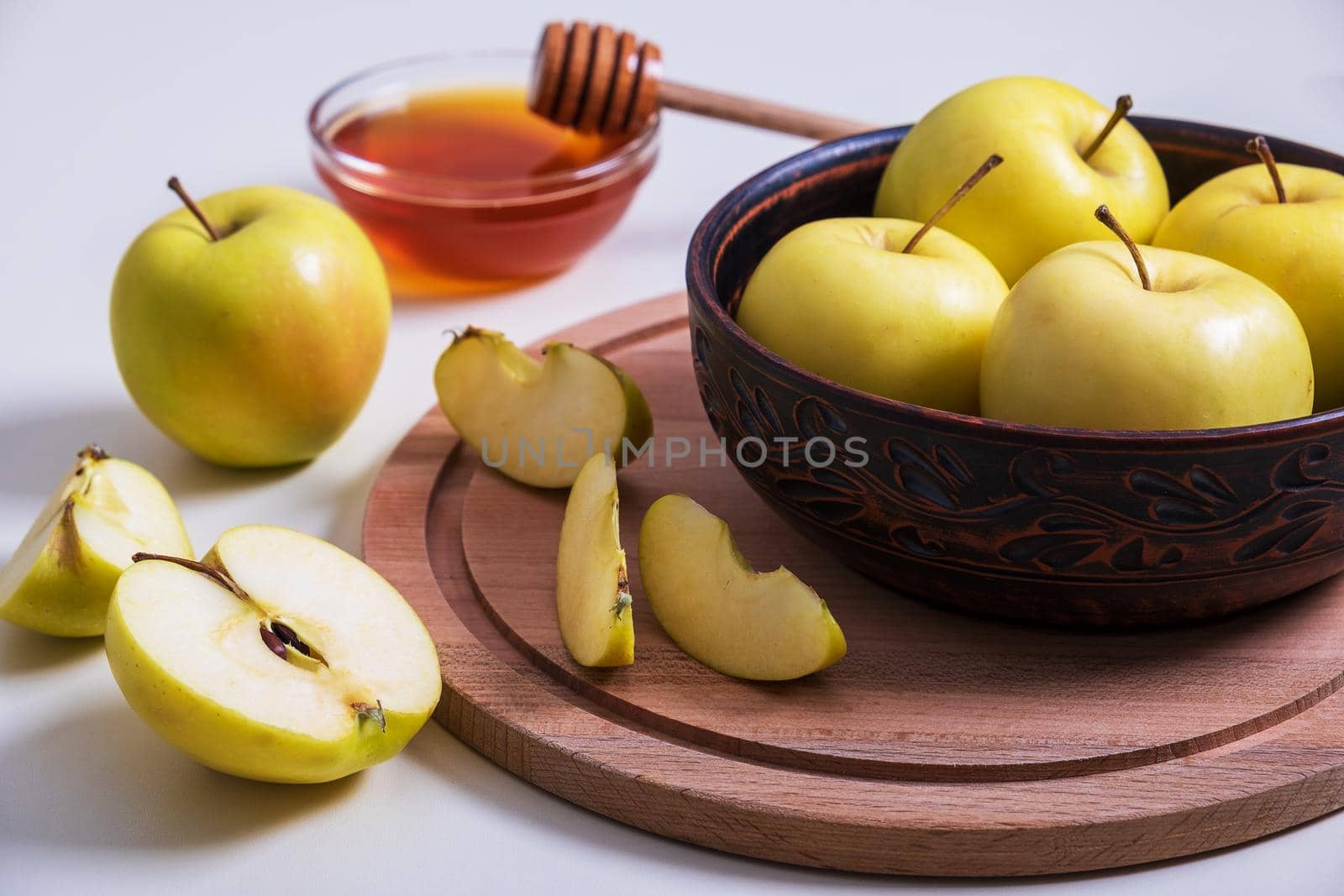Fresh ripe whole and cut yellow apples with honey lie on table. Selective focus.