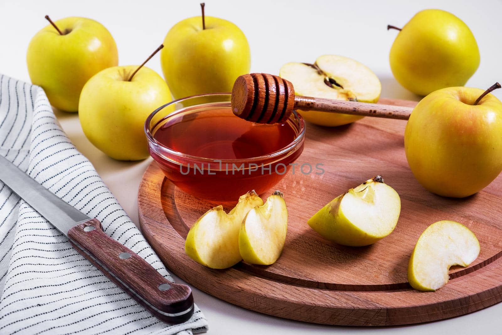 Fresh ripe whole and cut yellow apples with honey lie on table. Selective focus.