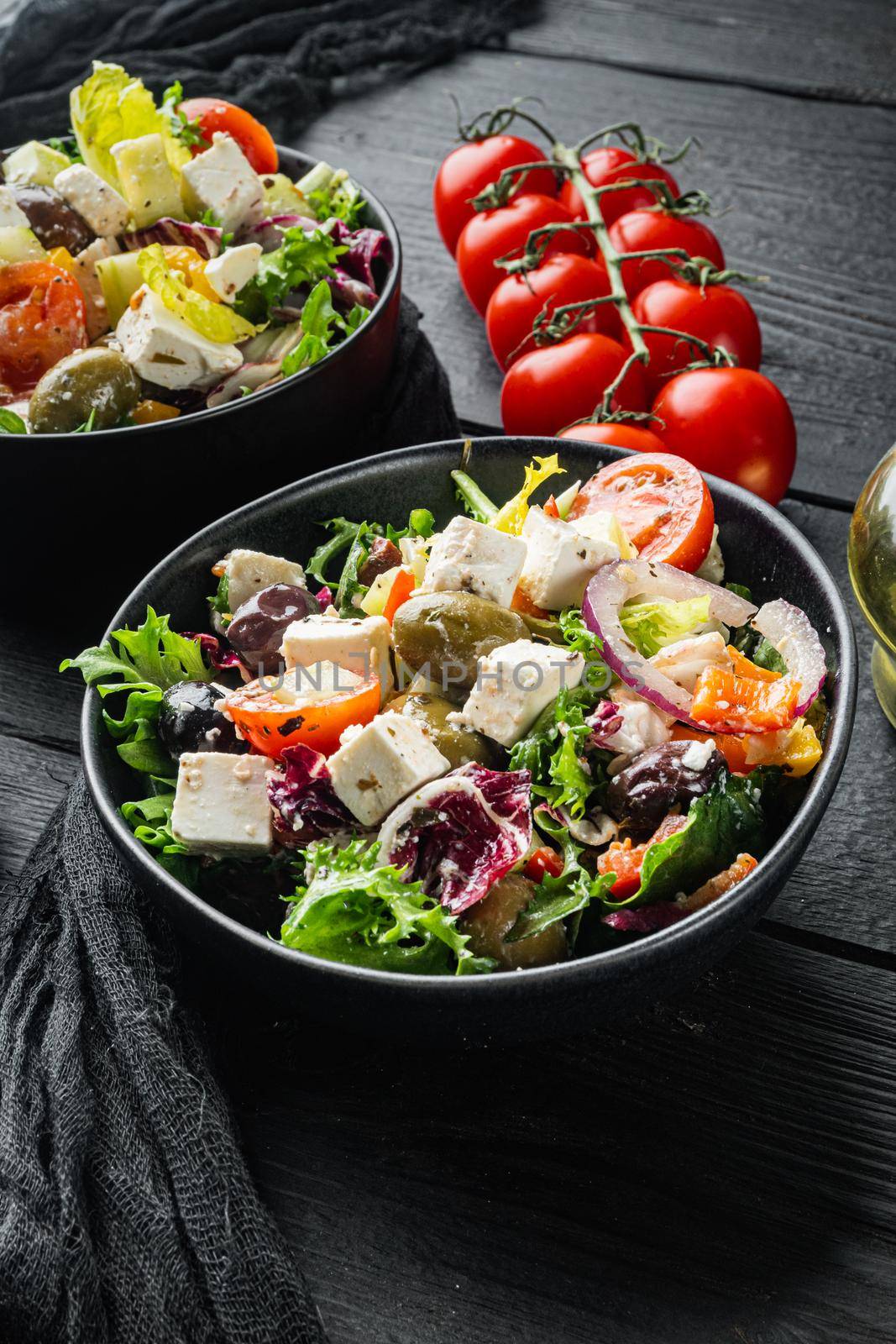 Greek salad with tomato pepper, olives and feta cheese, on black wooden table background