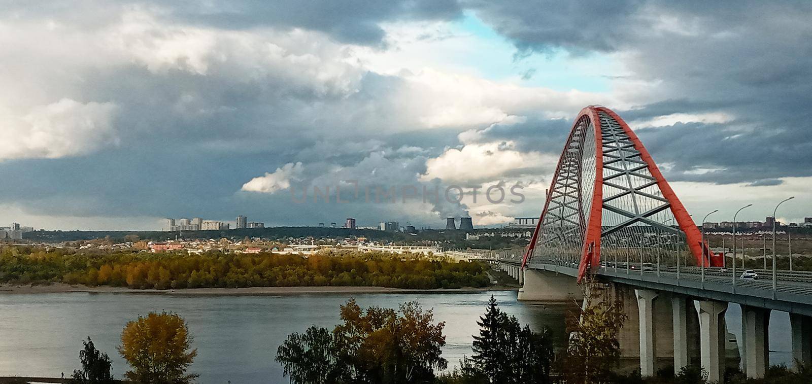 Red arch of the cable-stayed suspension bridge over the wide Ob River. Novosibirsk, Russia. Red suspension bridge over the Ob River. Bugrinsky bridge over the Ob River.