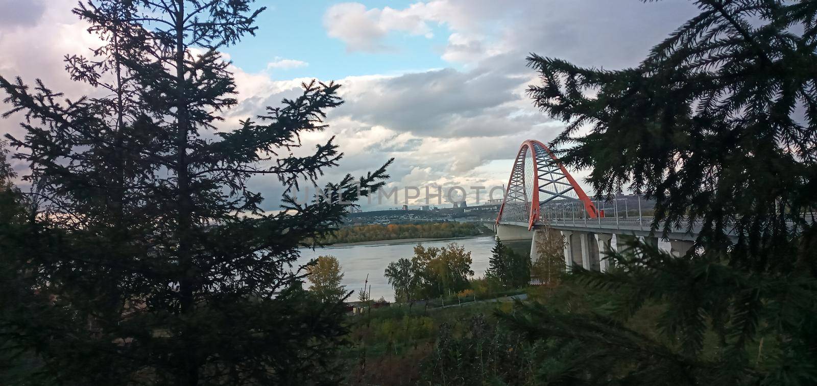Red arch of the cable-stayed suspension bridge over the wide Ob River. Novosibirsk, Russia. Red suspension bridge over the Ob River. Bugrinsky bridge over the Ob River.