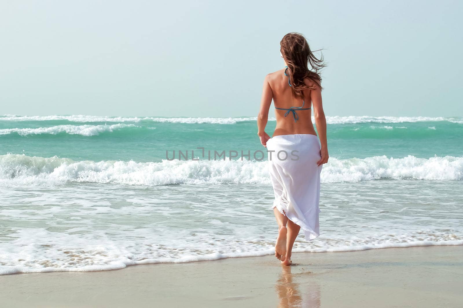 A beautiful girl is walking along the ocean shore. The concept of summer holidays