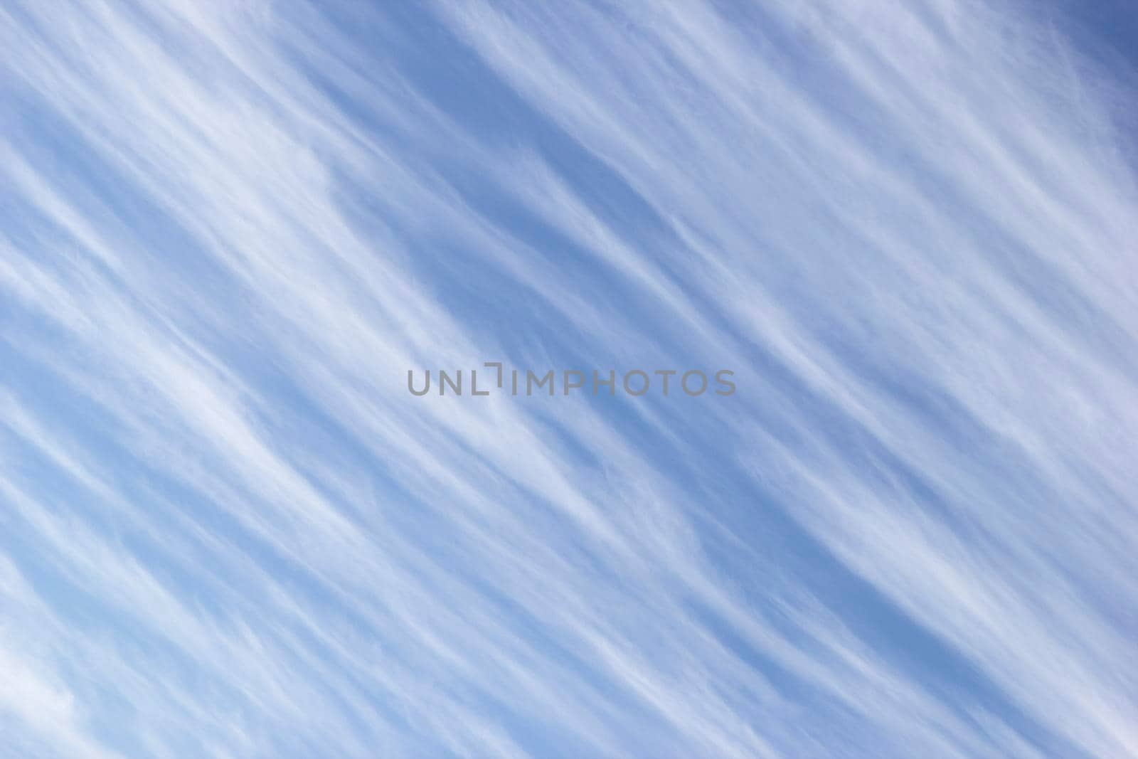 White clouds in form of diagonal stripes on background sky. by Laguna781