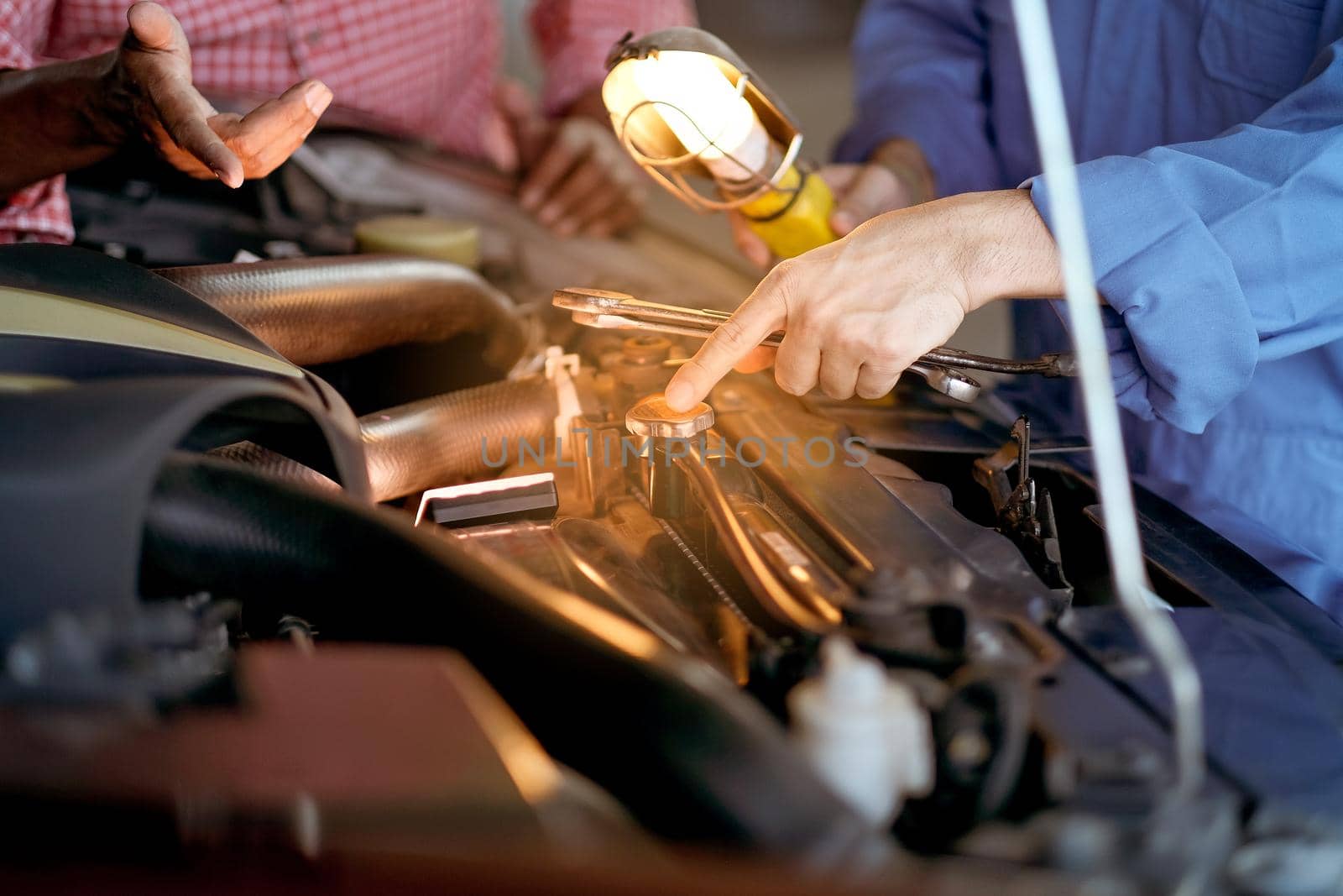 Hand of automotive mechanic with blue uniform point and show the problem about lid of radiator of car.