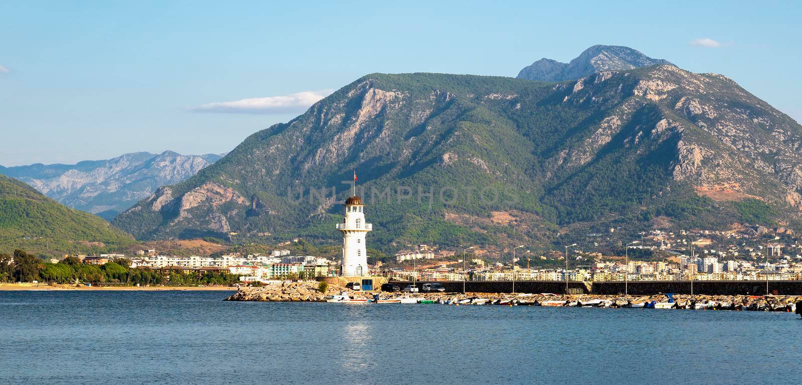 Turkey, Alanya - November 9, 2020: The old lighthouse in the port of Alanya against the backdrop of beautiful mountains. View from the sea.