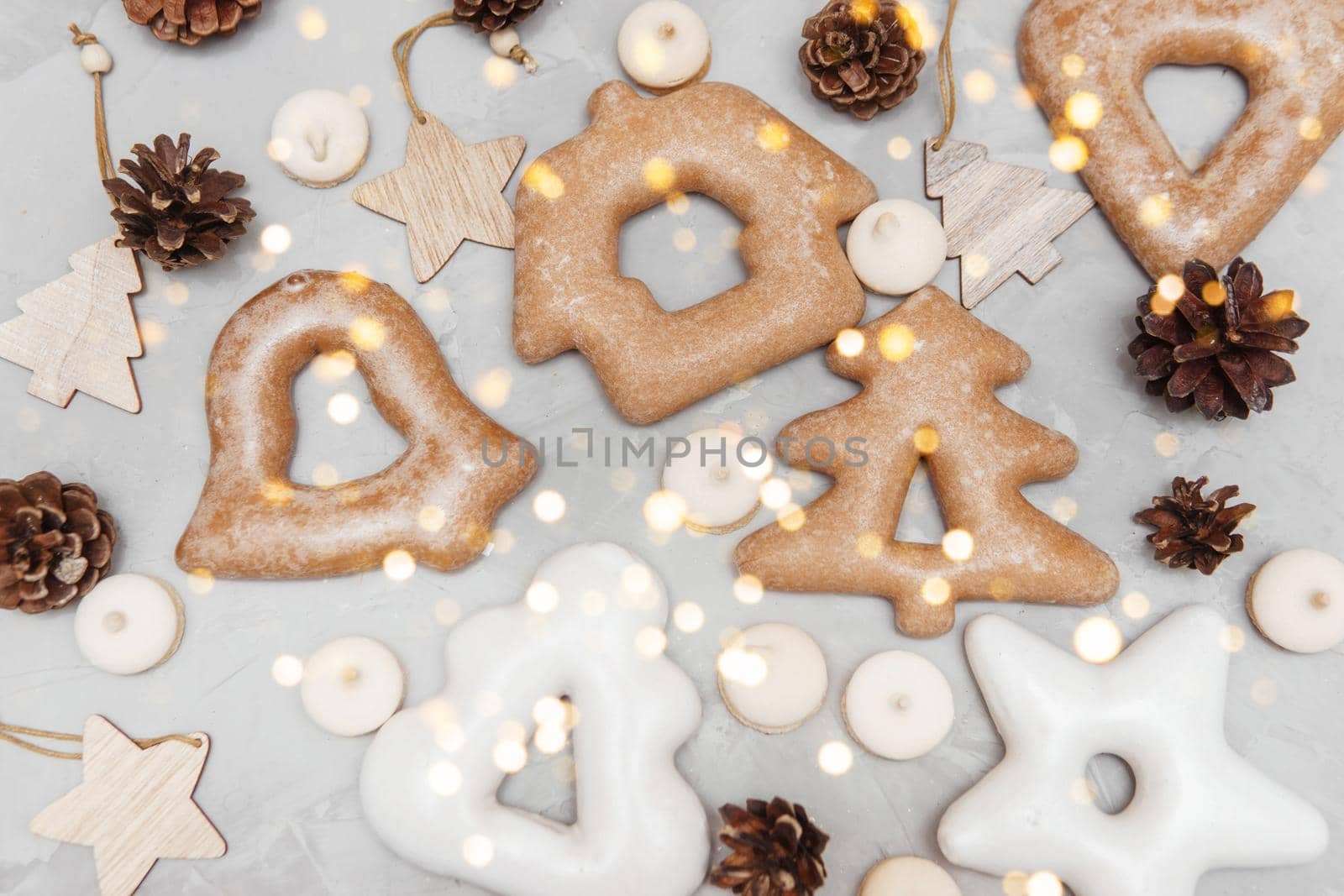 Banner for Christmas and New Year gingerbread stars, houses, Christmas trees, toys on a gray concrete background, Christmas lights bokeh in the foreground.