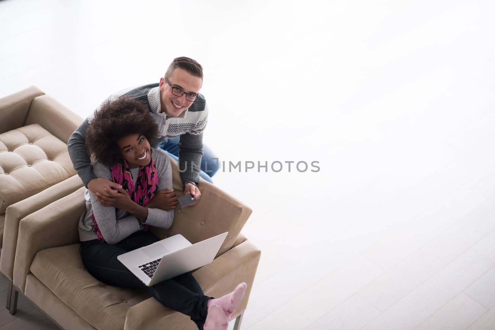 Happy young multiethnic couple shopping online through laptop using credit card at home