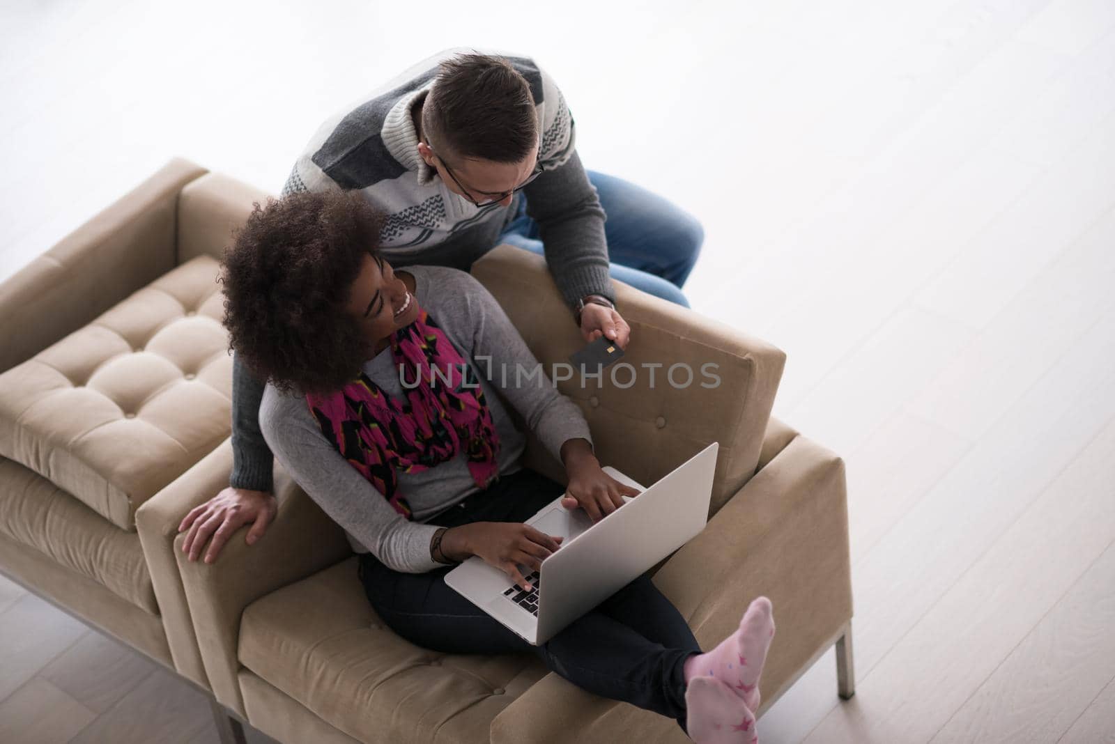 Happy young multiethnic couple shopping online through laptop using credit card at home