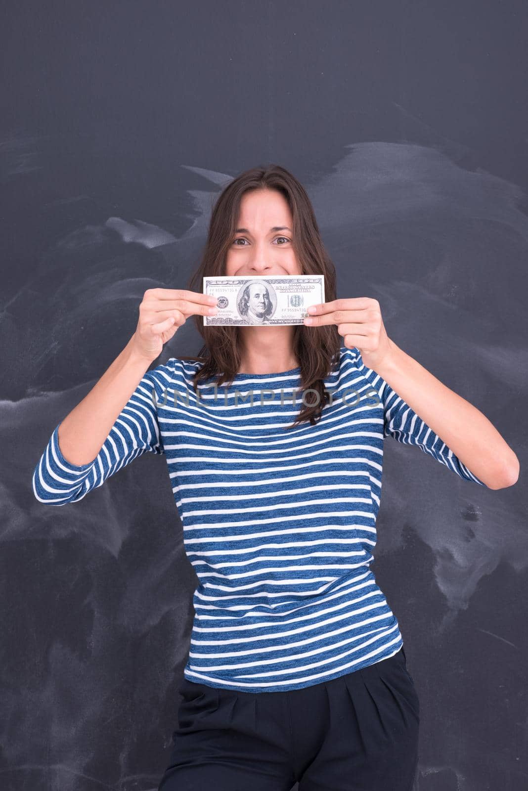 portrait of a young woman holding a banknote in front of chalk drawing board