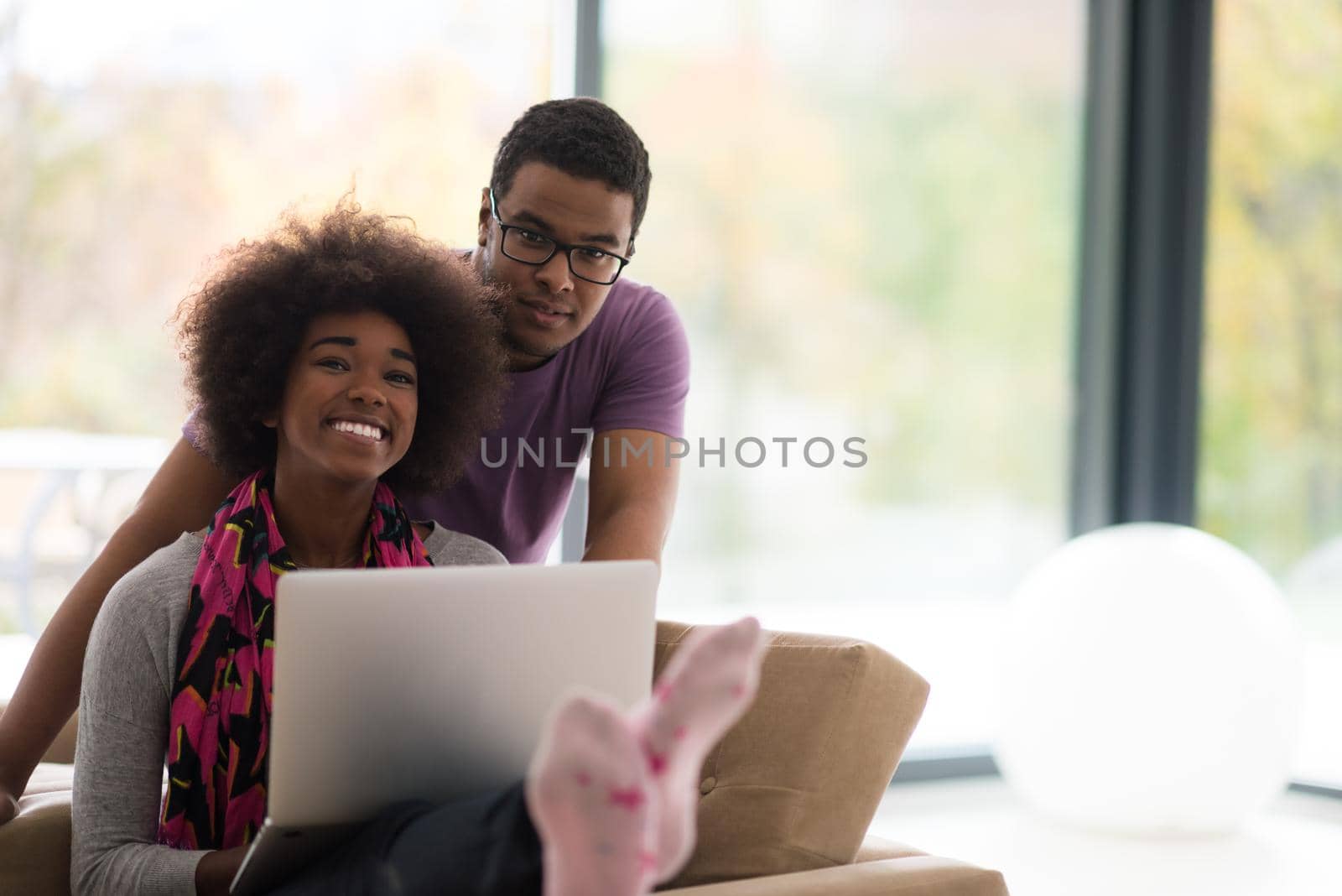 Happy young african american couple shopping online through laptop using credit card at home