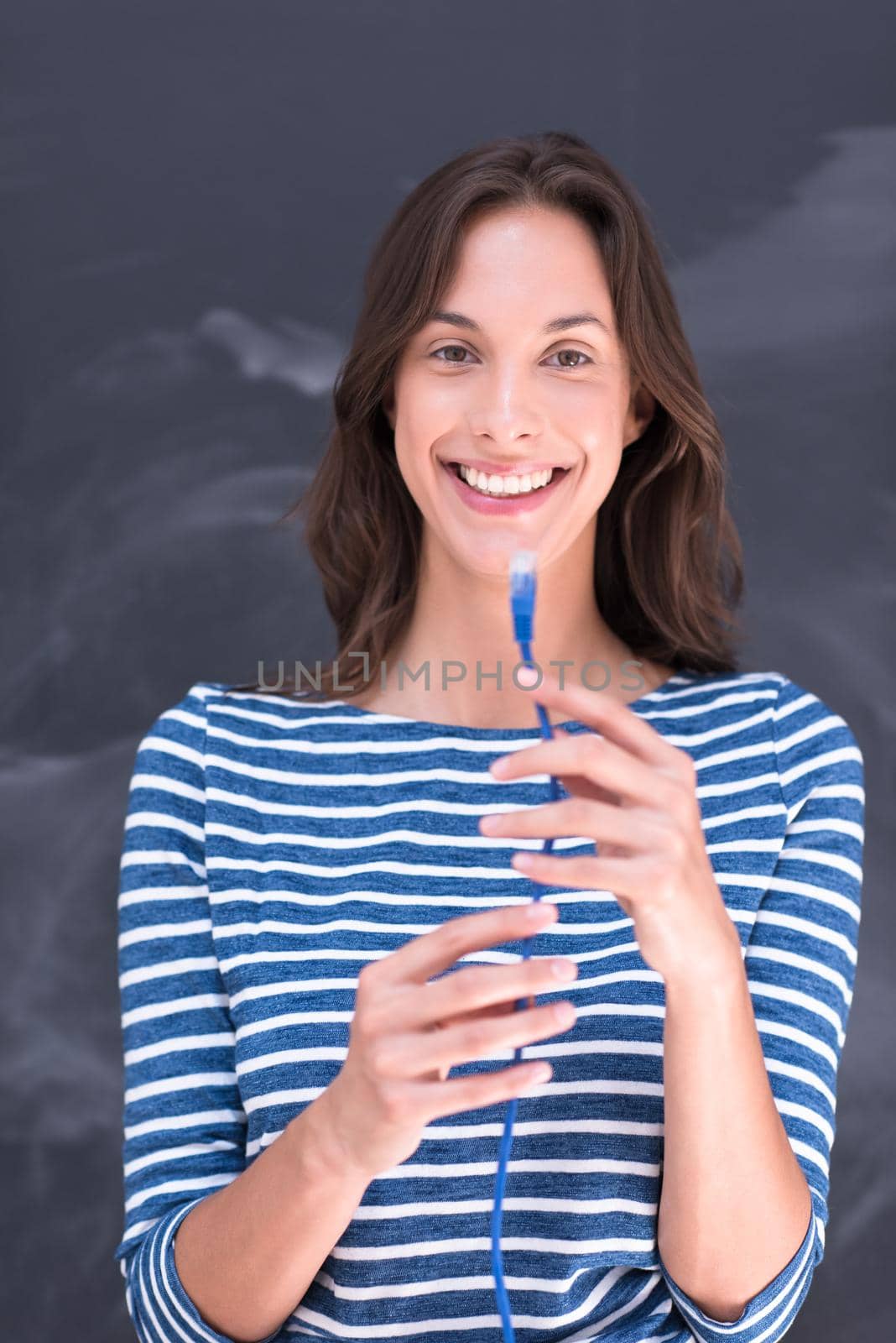 portrait of a young woman holding a internet cable in front of chalk drawing board