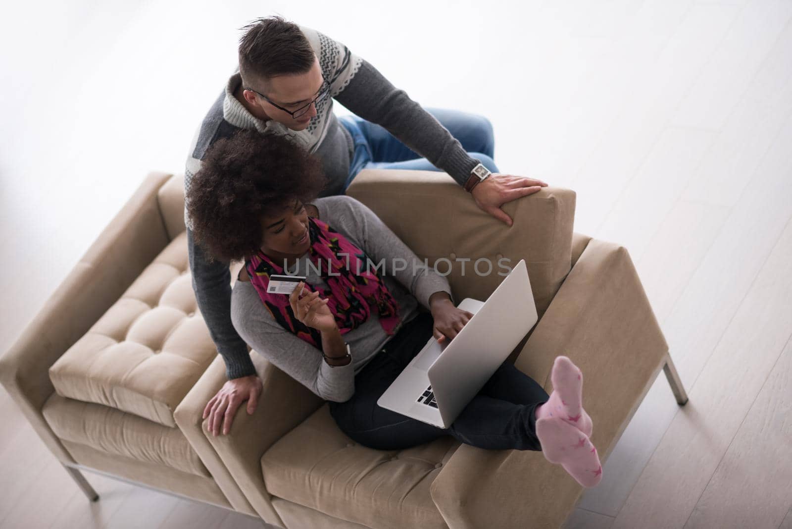 Happy young multiethnic couple shopping online through laptop using credit card at home