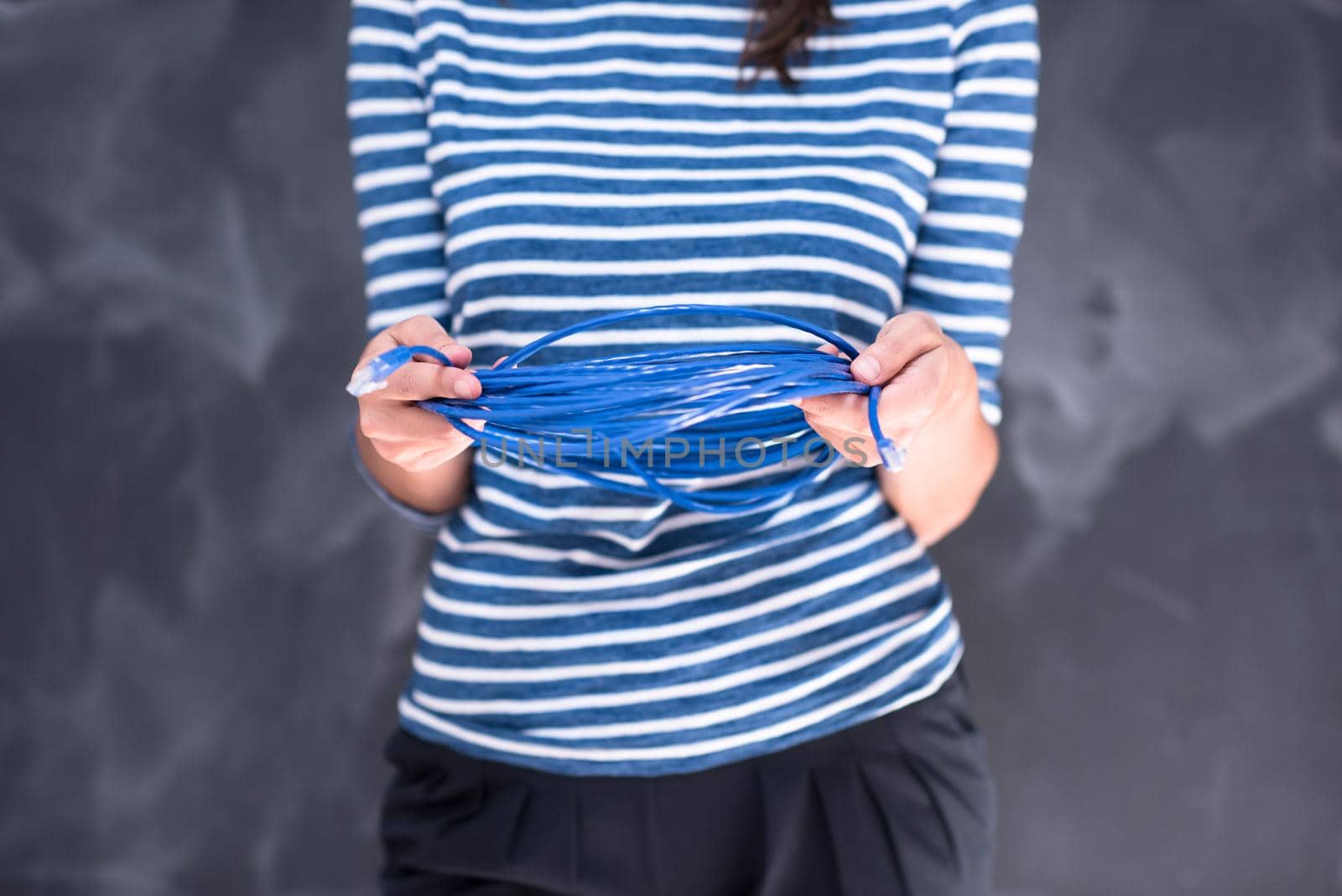 portrait of a young woman holding a internet cable in front of chalk drawing board