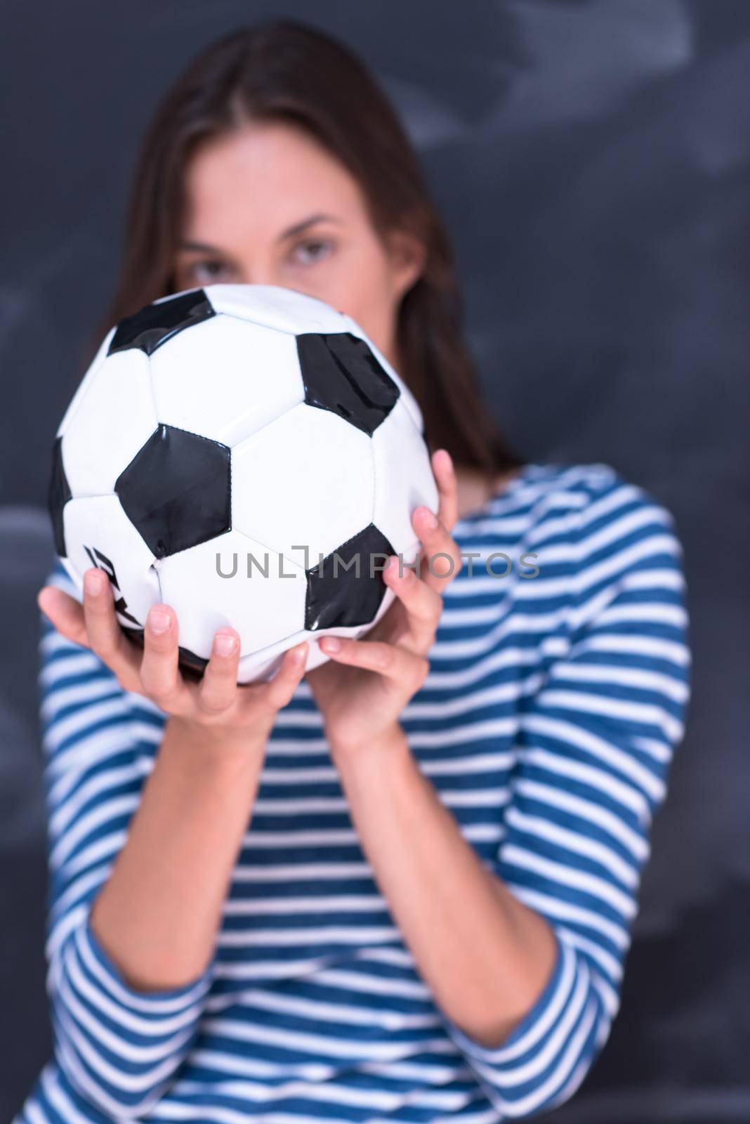 woman holding a soccer ball in front of chalk drawing board by dotshock