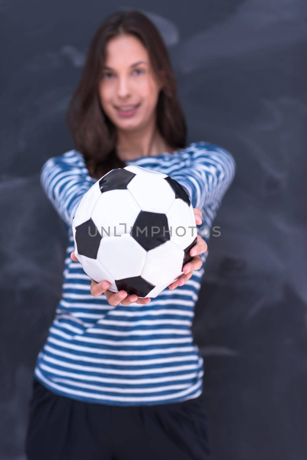 portrait of a young woman holding a soccer ball in front of chalk drawing board